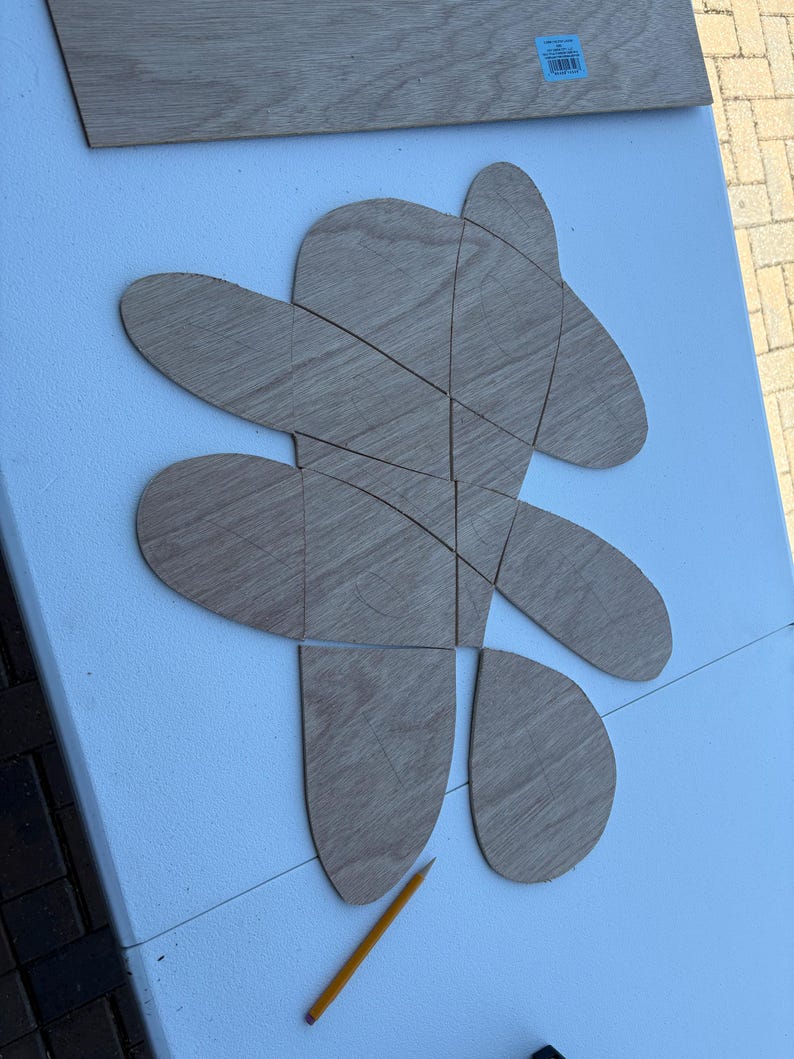 Freshly cut wooden shapes laid out on a table beside a pencil